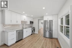 Kitchen featuring white cabinetry, stainless steel appliances, wood-finish flooring, recessed lighting, and a window - 