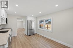 Kitchen featuring light wood-finish flooring, white cabinetry, recessed lighting, and stainless steel appliances - 