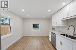 Kitchenette with white shaker cabinetry, stainless steel dishwasher, and a double basin sink with a gooseneck faucet - 