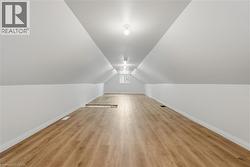 Spacious room featuring wood-finish flooring, white walls, and a sloped ceiling with recessed lighting - 