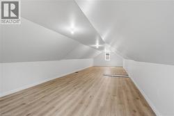 Expansive attic space featuring light wood-finish flooring, recessed lighting, and a window - 