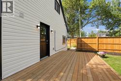 Expansive wood deck with a privacy fence, white siding, and exterior lighting fixtures - 