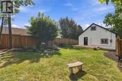 Expansive backyard featuring a manicured lawn, mature trees, and a wooden privacy fence - 