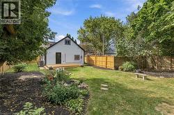 Expansive backyard featuring a manicured lawn, a wooden privacy fence, mature trees, and a ground-level wood deck - 
