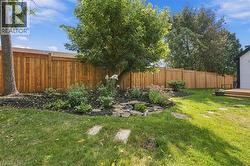 Expansive lawn area, wood privacy fencing, established tree, and a stone-edged garden bed - 