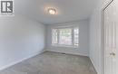 2nd Main Floor Bedroom featuring bay window with blinds, light gray wall paint, gray carpeting, white trim, and a ceiling-mounted light fixture and closet. - 25 Bankside Drive Unit# 2, Kitchener, ON 