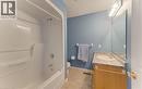 White shower/tub combination with chrome fixtures, wood-finish vanity with an integrated sink, patterned countertop, and a large mirror with overhead vanity lighting - 25 Bankside Drive Unit# 2, Kitchener, ON 