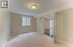 Carpeted room with a double-paned window, flush-mount ceiling light, and French doors featuring glass panels - 