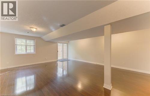 Spacious interior featuring wood-finish flooring, a window with horizontal blinds, and a sliding glass door to deck. - 25 Bankside Drive Unit# 2, Kitchener, ON 