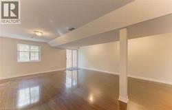 Spacious interior featuring wood-finish flooring, a window with horizontal blinds, and a sliding glass door to deck. - 