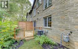 Stone exterior with multiple windows, leading to a wooden deck with dark balusters - 