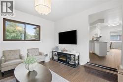 Wood-finish flooring throughout, with a large window and a contemporary chandelier - 