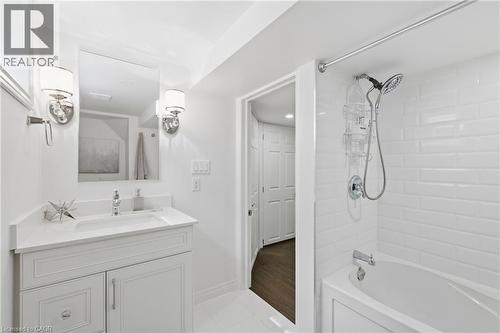 White shaker vanity with integrated sink, chrome faucet, and sconce lighting - 22 Sycamore Street, Hamilton, ON 