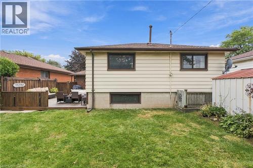 Expansive backyard featuring a wood deck, wood privacy fencing, and a manicured lawn - 22 Sycamore Street, Hamilton, ON 
