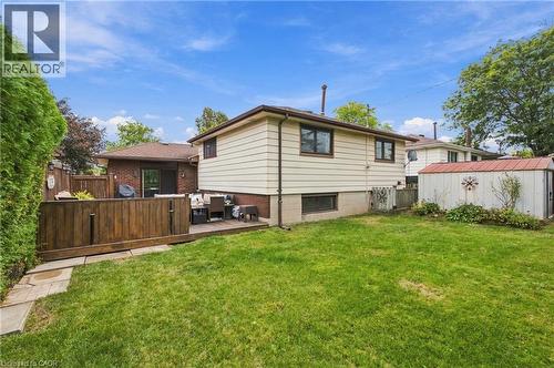 Expansive green yard with a wood deck, wood privacy fencing, and a storage shed with a metal roof - 22 Sycamore Street, Hamilton, ON 