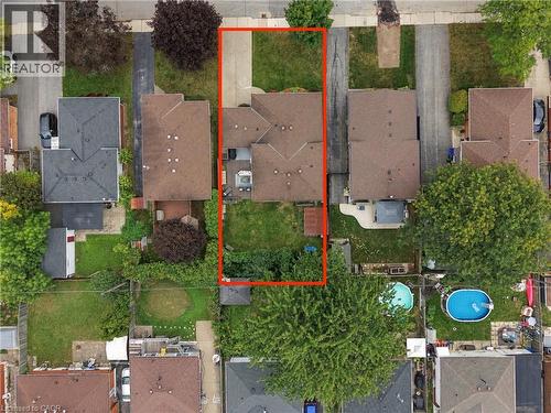 Aerial perspective showcasing the property's footprint, including a driveway, residential structure with a brown shingle roof, and a green grass lawn - 22 Sycamore Street, Hamilton, ON 