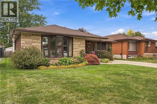 Brick and stone veneer exterior with a bay window, front lawn, and mature landscaping - 22 Sycamore Street, Hamilton, ON 