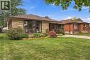 Brick and stone veneer exterior with a bay window, front lawn, and mature landscaping - 22 Sycamore Street, Hamilton, ON 