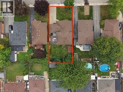 Aerial perspective showcasing the property's footprint, including a driveway, residential structure with a brown shingle roof, and a green grass lawn - 