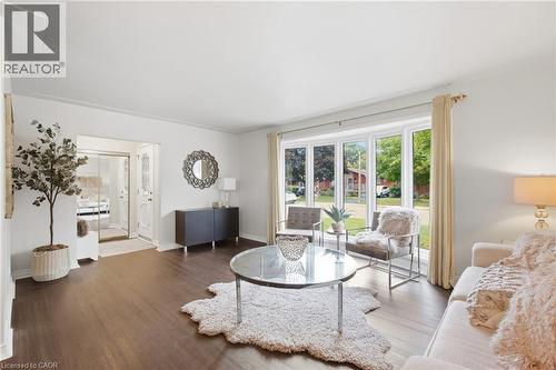 Dark wood-finish flooring, white walls, large bay window, recessed entryway, and a built-in console table - 22 Sycamore Street, Hamilton, ON 