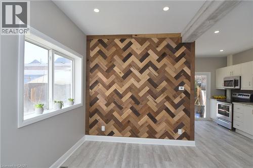Herringbone wood-finish accent wall, recessed lighting, light wood-finish flooring, white trim, and white double-pane window - 76 Burlington Street E, Hamilton, ON 