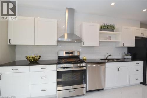 White shaker-style cabinetry, dark countertops, white subway tile backsplash, stainless steel appliances, and recessed lighting - 76 Burlington Street E, Hamilton, ON 