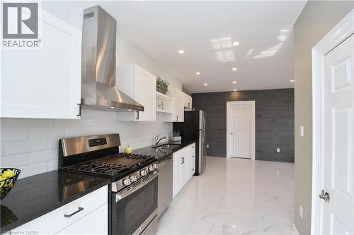 Kitchen featuring white shaker cabinetry, black countertops, stainless steel appliances, white subway tile backsplash, and recessed lighting - 76 Burlington Street E, Hamilton, ON 
