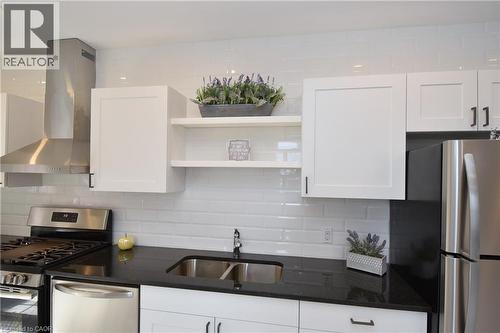Modern kitchen featuring white shaker-style cabinetry, dark countertops, white subway tile backsplash, and stainless steel appliances - 76 Burlington Street E, Hamilton, ON 