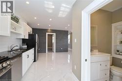 Kitchenette featuring white shaker cabinetry, dark countertops, a stainless steel sink, and a stainless steel range - 