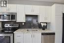 White shaker-style cabinetry, stainless steel appliances, granite-look countertops, and a dark mosaic tile backsplash - 76 Burlington Street E, Hamilton, ON 