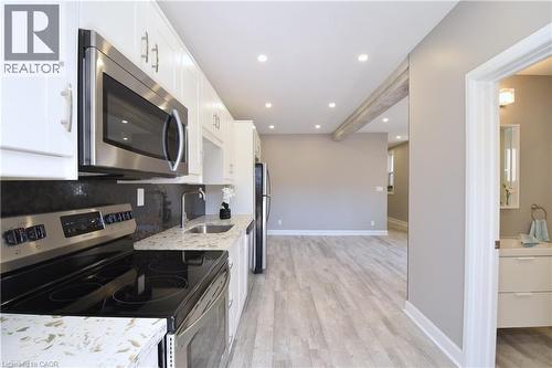Kitchen featuring white cabinetry, stainless steel appliances, speckled countertops, and recessed lighting - 76 Burlington Street E, Hamilton, ON 