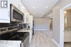 Kitchen featuring white cabinetry, stainless steel appliances, speckled countertops, and recessed lighting - 