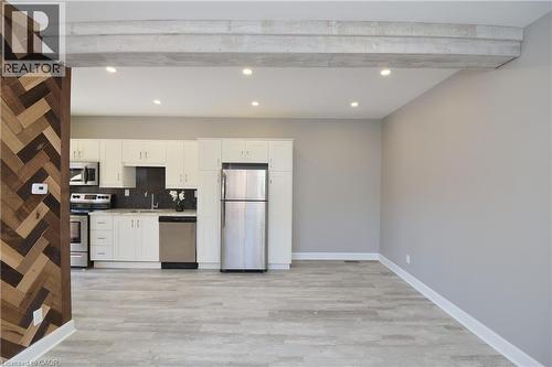 Kitchen featuring white cabinetry, stainless steel appliances, and light-colored countertops - 76 Burlington Street E, Hamilton, ON 