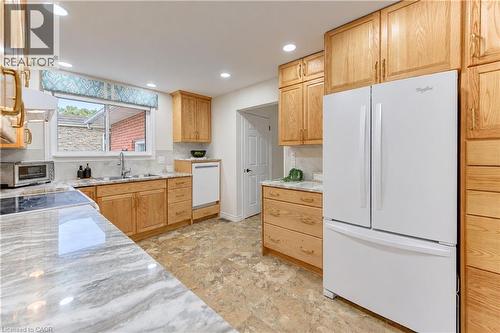Full-height wood cabinetry, integrated white appliances, and light-toned countertops - 422 Grangewood Drive, Waterloo, ON 