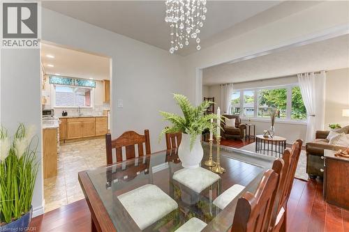 Dining area featuring a crystal chandelier, wood-finish flooring, and an open doorway to the kitchen - 422 Grangewood Drive, Waterloo, ON 