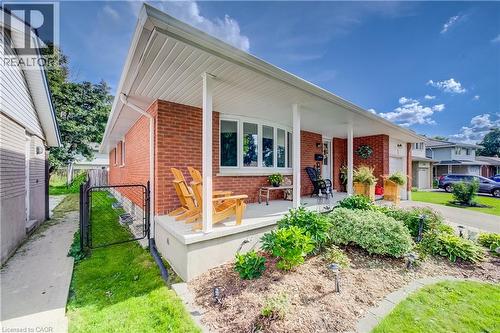 Brick facade with a covered front porch, Bay window, and mature front landscaping - 422 Grangewood Drive, Waterloo, ON 