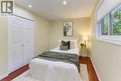 Recessed lighting, wood-finish flooring, white window trim, and a built-in closet with bi-fold doors - 