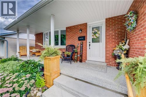 Brick exterior with white trim, covered front porch, concrete steps, and a bay window - 422 Grangewood Drive, Waterloo, ON 