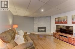 Hardwood-style flooring, a built-in fireplace with a stone surround, recessed lighting, and a drop ceiling - 