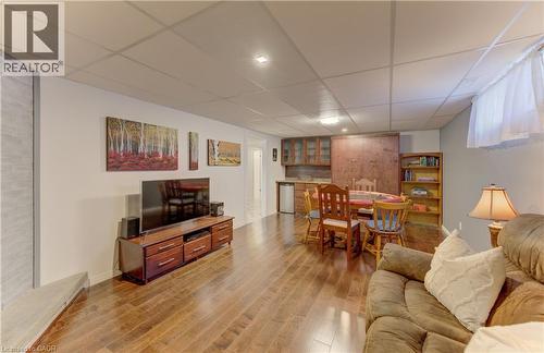 Wood-finish flooring throughout, recessed lighting, built-in shelving, and a wet bar with wood cabinetry - 422 Grangewood Drive, Waterloo, ON 