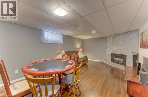 Wood-finish flooring throughout, gray painted walls, a drop ceiling, and a brick-finish fireplace with an insert - 422 Grangewood Drive, Waterloo, ON 