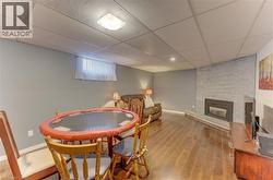 Wood-finish flooring throughout, gray painted walls, a drop ceiling, and a brick-finish fireplace with an insert - 