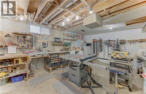 Unfinished basement workshop with exposed ceiling joists, white painted walls, and built-in workbenches - 422 Grangewood Drive, Waterloo, ON 