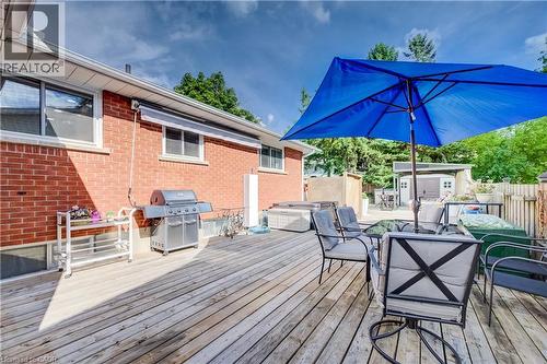Expansive wooden deck with brick exterior, featuring a built-in hot tub and a separate shed structure - 422 Grangewood Drive, Waterloo, ON 