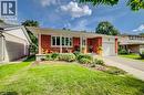Red brick exterior with white trim, covered front porch, integrated garage, and a landscaped front yard - 422 Grangewood Drive, Waterloo, ON 