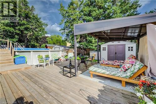 Expansive wood-finish deck featuring an above-ground pool with stairs, a covered patio area, and a storage shed - 422 Grangewood Drive, Waterloo, ON 