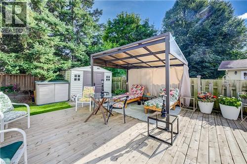 Wood-finish deck with a covered pergola featuring opaque panels, privacy curtains, and a storage shed - 422 Grangewood Drive, Waterloo, ON 