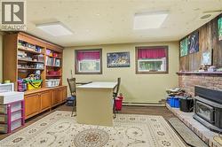 Built-in wood cabinetry with open shelving, wood-finish flooring, and brick fireplace with wood-burning insert - 