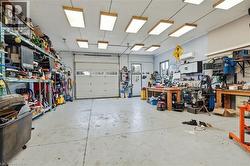 Spacious workshop with a large overhead door, multiple fluorescent ceiling fixtures, and expansive concrete flooring - 
