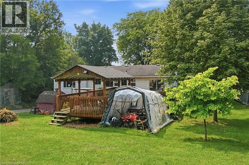 Expansive backyard featuring a manicured lawn, established trees, and a wooden deck with a covered pergola - 1311 W Concession 6 Road, Flamborough, ON 